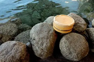 Una peque&ntilde;a cubeta descansando en la rocas a la orilla de la tina