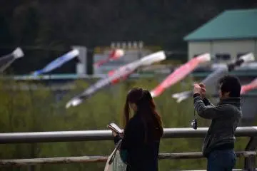 A couple on the bridge taking photos of the carp streamers over the river