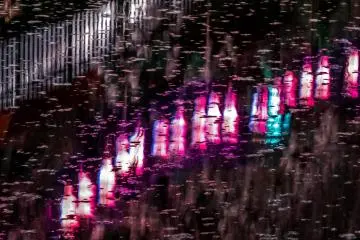 Falling raindrops compete with the colorful tones of several dozen lanterns reflecting off the river