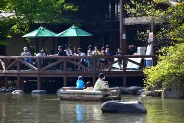 <p>A family enjoying rafting and people taking a break on the open deck of cafe 'Woodhouse Kuzuryu' beside the pond.</p>
