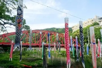 Bendera ikan koi membuat pemandangan indah dengan jembatan merah sebagai latar belakangnya
