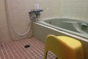 Simple bath and shower area at Takamatsuya Japanese inn