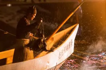 <p>A cormorant sprays the fisherman with water</p>