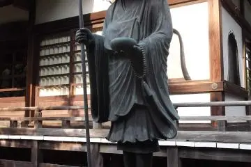 <p>A statue of a pilgrim whose hat is very effective at shielding his face from the sun</p>