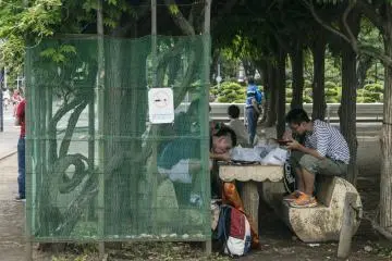 <p>Too old for the mini-themepark? These teens know how to entertain themselves, chowing down yakisoba under the shade.</p>