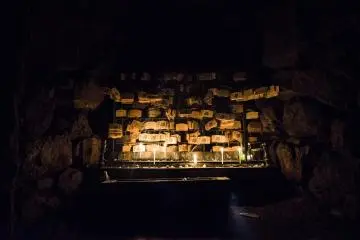 <p>Dark except for the warm glow of candlelight, hundreds of votive tablets are hung wishing for relieve from eye ailments.</p>