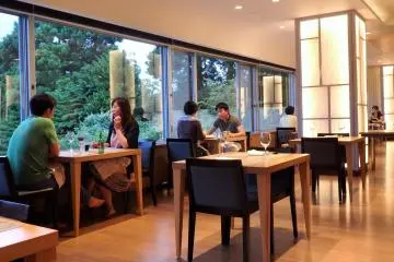 <p>Meals are served at regular tables in this dining room overlooking surrounding greenery.</p>