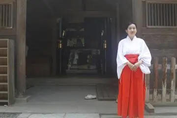 <p>A women stands next to the main shrine.</p>
