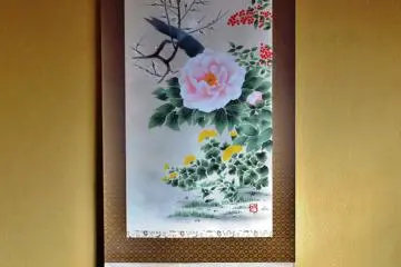 A vividly painted scroll hanging in an alcove, surrounded by brilliant celadon vases