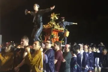 <p>Women chanting while balancing on shrines carried by eager volunteers</p>