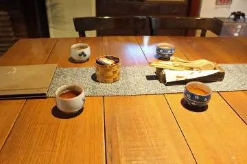 <p>Tea, oshibori cloths in their woven bamboo basket and other utensils</p>