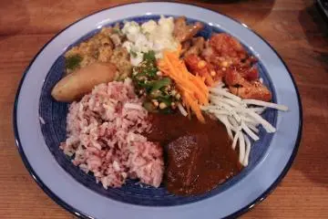 Buffet plate with curry and vegetable side dish selection.