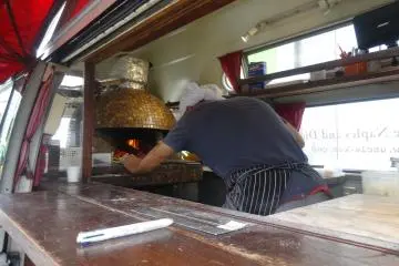 A chef cooks pizza in a real brick oven in his food truck