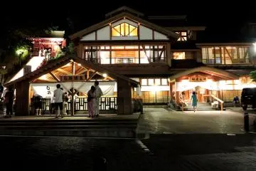<p>Sur la gauche, des marches illumin&eacute;es m&egrave;nent &agrave; un temple, et au premier plan se trouve un petit sanctuaire o&ugrave; les gens jettent des pi&egrave;ces de monnaie</p>