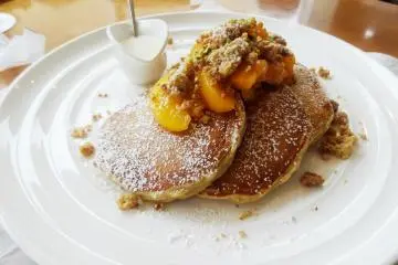 <p>Seasonal pancakes topped with peaches and streusel nut topping</p>