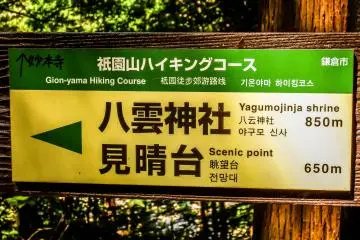 <p>A course marker with some hand written characters in black pen pointing towards Myohonji Temple, located several meters below</p>