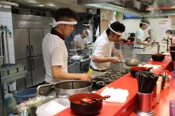 <p>Chefs hard at work preparing a dozen ramen servings at once.</p>
