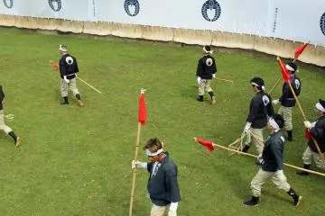 The bamboo poles and red flags recall a matador's cape