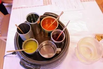 <p>Various liquid wax pots. The pot of clear wax at the bottom was used to finish and seal the candles made</p>