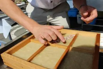 <p>The decorations are laid right on top of the paper. The water in the pulp glues them down</p>