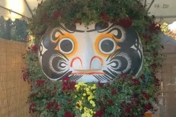 <p>Boneka Daruma didekorasi dengan menggunakan daun dan bunga</p>