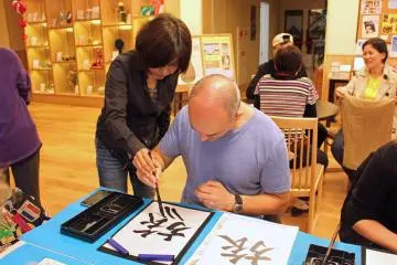 <p>One of the instructors lends a helping hand. The kanji is "tabi," meaning trip or journey</p>