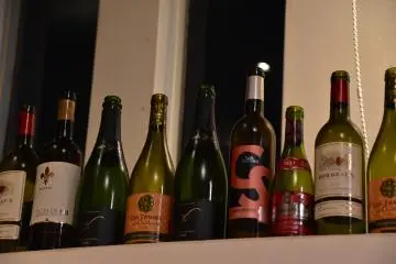 <p>Botol-botol wine kosong berbaris di rak&nbsp;</p>
