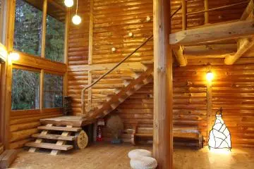 <p>The Log House's common space. A wood burning fireplace/stove, a swing, enormous windows and stools and pillows for sitting on the floor are available</p>

