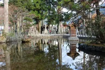 <p>Stone and wooden monuments reflected in the large pond</p>
