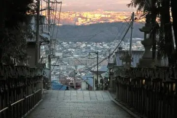 <p>The buildings and homes of Nara and Ikoma Cities glow fiery orange in the sunset before being swallowed by the shadow of Mt. Ikoma</p>
