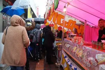 <p>Huddled in raincoats and under umbrellas, locals wait in line for delicious street food.</p>
