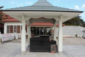 An offertory box and incense altar in front of the shop.  The red roofed shop sells the entrance tickets as well as souvenirs and religious items.