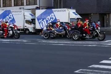 Motorcyclist group wearing Santa costumes passing by Kyoto City Hall during the Christmas season