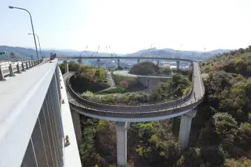 You are rewarded for making such a long crossing with a pleasantly curving downslope ramp towards Sunrise Itoyama. Congratulations for completing the Shimanami Kaido!