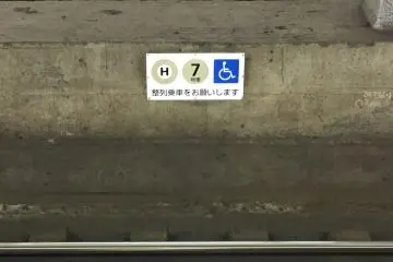 A sign on the Hibiya line tracks as seen from the platform, indicating that this approaching train car will feature priority wheelchair boarding/extra space
