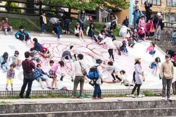 Kids sliding down the side of the river bank.