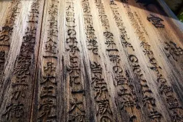 Wooden board explaining the shrine's history is bleached by the sun