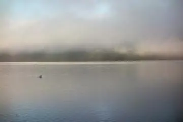 Les premiers rayons de lumière illuminent la bordure des nuages sur le lac