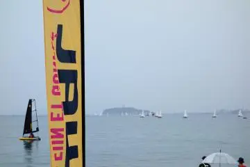 Tiwal Japan's flag flutters in the breeze as people take Tiwal Japan's sailing dinghy out for a spin in the background