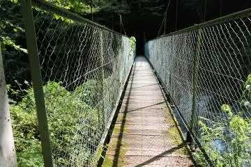 Narrow suspension bridge over a river crossed by the trail