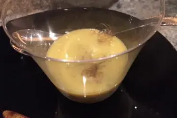 Corn soup after releasing the smoke served with a baby corn on a skewer