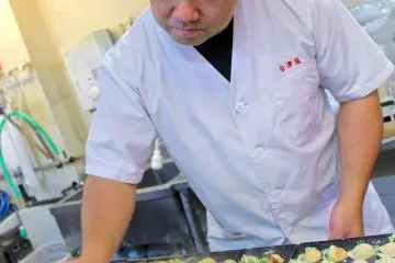 Chef making takoyaki at Aizuya at Tempozan Marketplace. The Palm-Auth-Pay app works here.