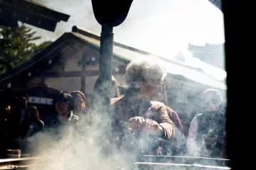 A woman purifies herself with waves of smoke