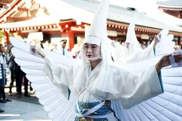 Herons are dressed with white wings that blend in with heron headpieces, sky blue pants embroidered with gold print.