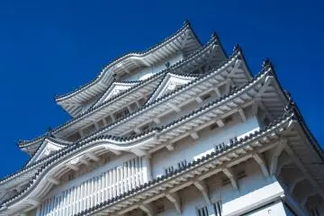 Looking up at blue skies behind Himeji Castle