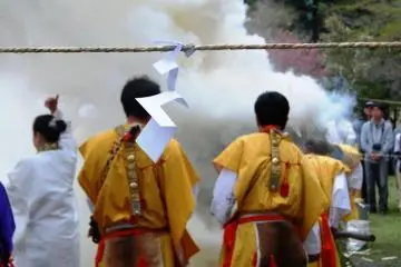 The fire is lit from the front and from the back. Yamabushi are controlling the fire and springle some water into it to increase the purifying smoke. In the back a woman is performing a sacred dance
