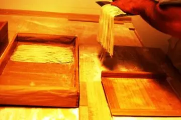 Memindahkan setiap pisau yang penuh dengan soba dengan hati-hati ke dalam sebuah kotak kayu