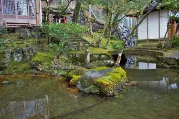 A small pond in front of a small shrine