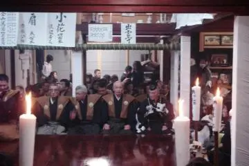 Candles, lanterns, stripes of white paper with the names of the plays and stripes of white paper cut in zigzag pattners, like you find at shrines in Japan, decorate the room