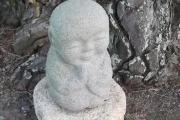 A tiny statue at the base of the big tree